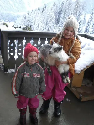 two children standing next to each other holding a goat at Niederhaushof in Santa Valburga St. Walburg