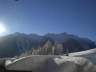 a snow covered hill with trees and mountains in the background at Niederhaushof in Santa Valburga St. Walburg