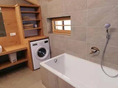 a bathroom with a tub and a washing machine at Niederhaushof in Santa Valburga St. Walburg