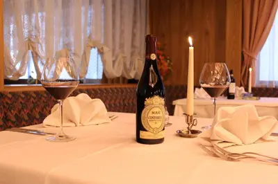a bottle of wine sitting on a table with wine glasses at Hotel Centrale in Alleghe
