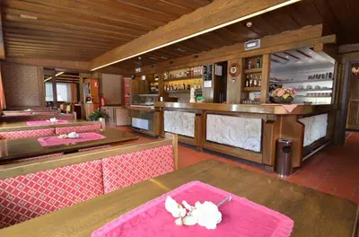 a restaurant with pink tables and a bar at Hotel Centrale in Alleghe