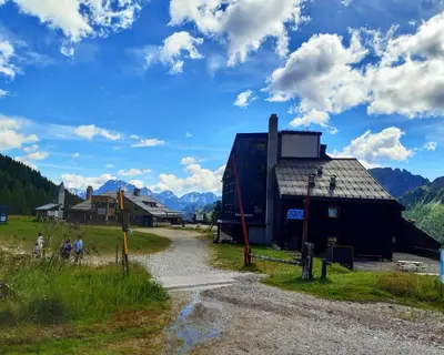 a barn in a field with mountains in the background at Il Cirmolo delle Saline in Falcade