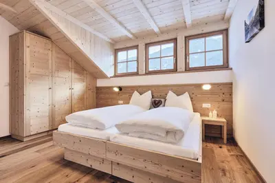 a bedroom with a large white bed in a attic at Huberhof in San Lorenzo di Sebato