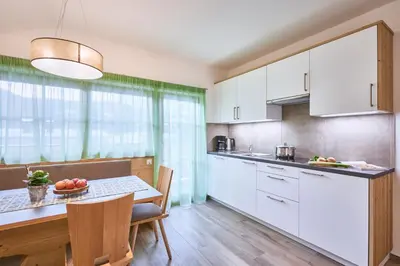 a kitchen with white cabinets and a table with a bowl of fruit at Huberhof in San Lorenzo di Sebato