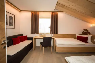 a room with two beds and a desk and a table at Appartamenti Te Paisc in La Villa