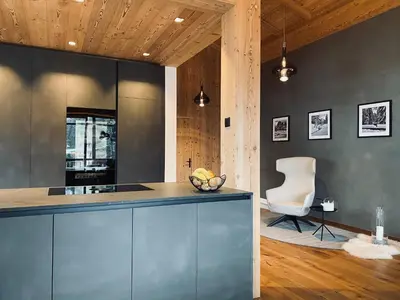 a kitchen with gray cabinets and a white chair at Florisa Mountain Penthouse in San Vigilio Di Marebbe