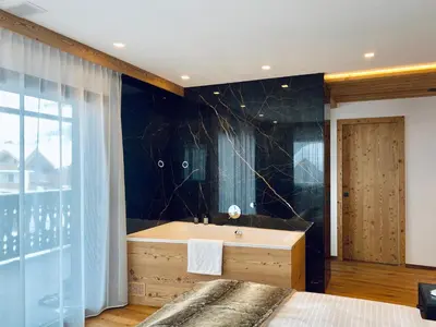 a bathroom with a tub and a black wall at Florisa Mountain Penthouse in San Vigilio Di Marebbe