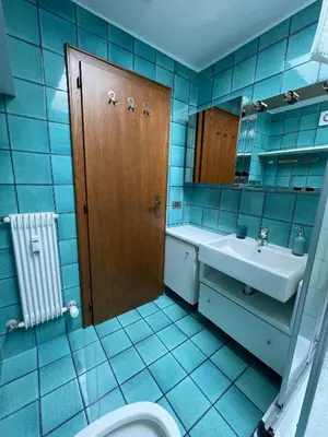 a blue tiled bathroom with a toilet and a sink at Les Corcelles in San Vigilio Di Marebbe