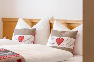 a bed with white pillows with red hearts on them at Apartment Sabrina in Santa Cristina in Val Gardena