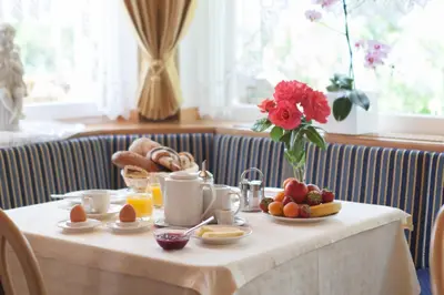 a table with breakfast foods and a vase of flowers at Appartements Verdinserhöhe in Schenna