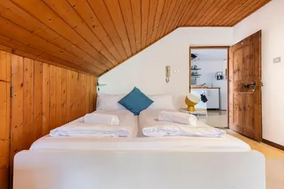 a bedroom with a large white bed with a wooden ceiling at Privatzimmervermietung Messner in Rifiano