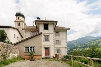 an old building with a clock tower on a hill at Privatzimmervermietung Messner in Rifiano