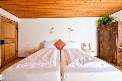a bedroom with a bed with white sheets and a wooden ceiling at Privatzimmervermietung Messner in Rifiano