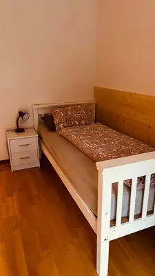 a bedroom with a white bed and a night stand at Appartement Alois in Bressanone