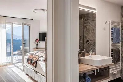 a bathroom with a sink and a bedroom with a view at Romy & Johannes Guesthouse in Schenna