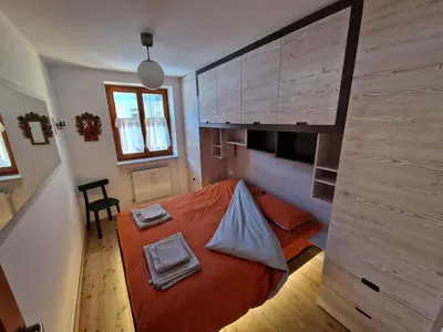 a small bedroom with a bed with orange sheets at Ampio appartamento su 2 livelli con garage coperto in Valdaora