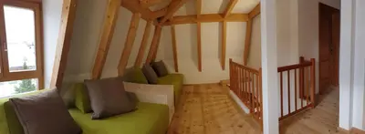 a living room with a green couch and wooden floors at Ampio appartamento su 2 livelli con garage coperto in Valdaora