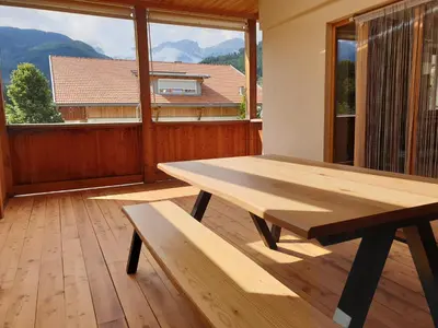 a wooden picnic table in a room with a large window at Ampio appartamento su 2 livelli con garage coperto in Valdaora