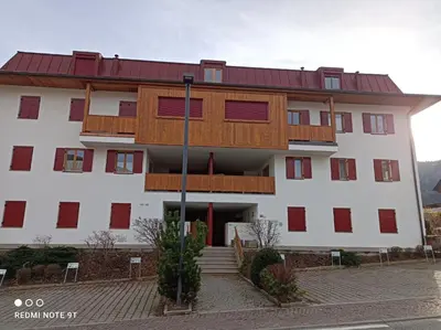 a large white building with red and wooden windows at Ampio appartamento su 2 livelli con garage coperto in Valdaora