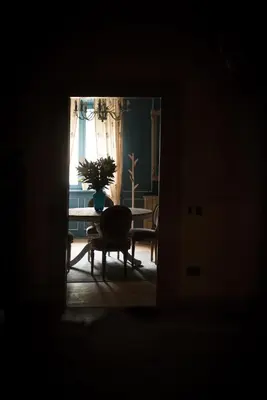a dark room with a table and a chair and a window at La Cles Deluxe Suites in Cles
