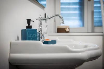 a white sink in a bathroom with a bottle of soap at La Cles Deluxe Suites in Cles