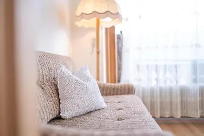 a couch with two pillows on it with a lamp at Der Ruibacher in Marlengo