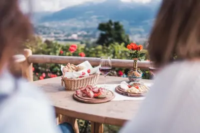 a table with a plate of food and a glass of wine at Der Ruibacher in Marlengo