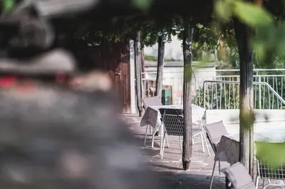 a table and chairs on a patio with trees at Der Ruibacher in Marlengo