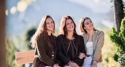three women sitting next to each other on a bench at Der Ruibacher in Marlengo