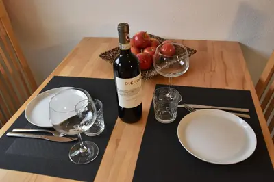 a table with a bottle of wine and a bowl of fruit at Ferienwohnungen Pircher in Rablà