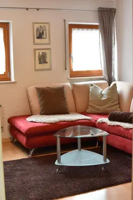a living room with a red couch and a glass table at Ferienwohnungen Pircher in Rablà