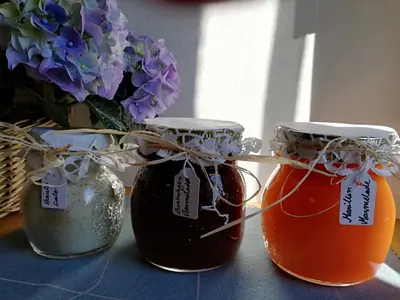 three jars of honey next to a vase of flowers at Ansitz Grustdorf in Appiano sulla Strada del Vino