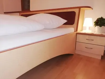 a bed with a wooden headboard and a night stand with a lamp at Ansitz Grustdorf in Appiano sulla Strada del Vino