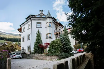 a large white building with cars parked in front of it at Residence Castel in Ortisei