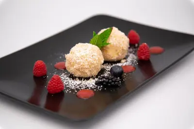 a black plate with a dessert with strawberries and powdered sugar at Gasthof Wunder in Auna di Sotto