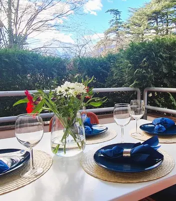 a table with plates and glasses and a vase with flowers at Appartamento Nadia, bilocale nel verde a 5 minuti dal centro in Merano