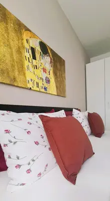 a bedroom with a bed with red pillows and a painting at Appartamento Nadia, bilocale nel verde a 5 minuti dal centro in Merano