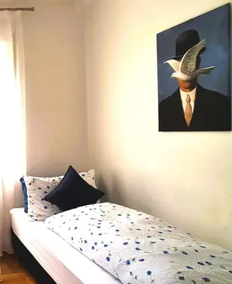 a bedroom with a painting of a man in a hat at Appartamento Nadia, bilocale nel verde a 5 minuti dal centro in Merano