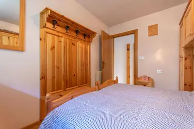 a bedroom with a bed and a wooden cabinet at Residence Sas de le Undesc in Soraga