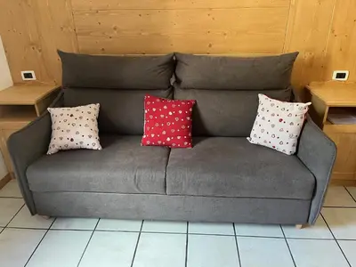 a grey couch with four pillows on it at CIASA SORES in Moena
