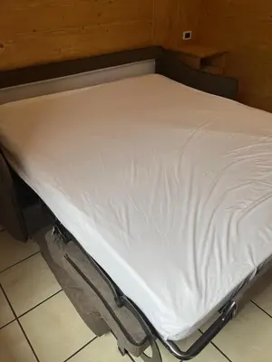 a bed with white sheets on it in a room at CIASA SORES in Moena