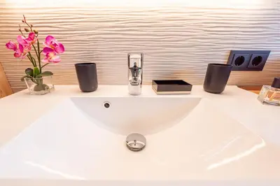 a white sink with a vase of flowers on a counter at Luxury Chalet Trumpfer in Riscone