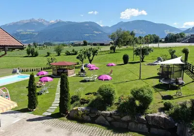 a garden with pink umbrellas and a swimming pool at Residence Untermoarhof in Brunico