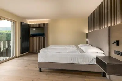 a bedroom with a large bed and a balcony at MONTARA living mountain air in Terento