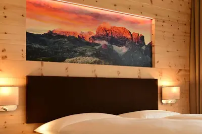 a bedroom with a large painting on the wall at MONTARA living mountain air in Terento