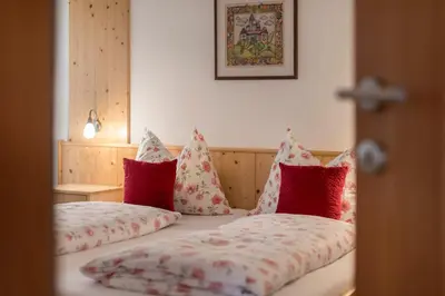 a bed with red and white pillows on it at Obereggerhof - Urlaub auf dem Bauernhof - Ferienwohnungen - Gitschberg Jochtal - Rio di Pusteria in Valles