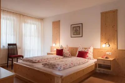 a bedroom with two beds and a chair in it at Obereggerhof - Urlaub auf dem Bauernhof - Ferienwohnungen - Gitschberg Jochtal - Rio di Pusteria in Valles