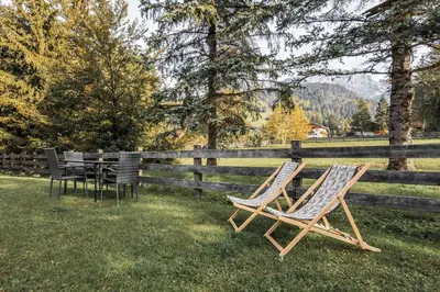 two chairs sitting in the grass next to a fence at DACIASA Apartment in San Vigilio Di Marebbe