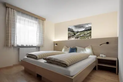 a bed in a bedroom with a large window at DACIASA Apartment in San Vigilio Di Marebbe