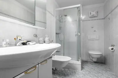 a white bathroom with a sink and a shower at DACIASA Apartment in San Vigilio Di Marebbe